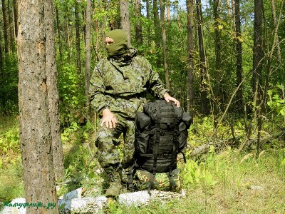 На фото человек в камуфляже «Горка-4» анорак ФСБ в зеленой смешанном лесу.