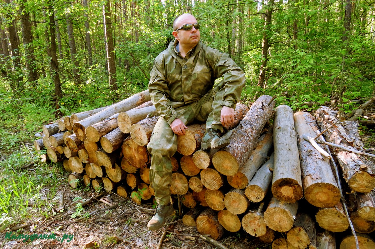 На фото автор обзора в Горке и ботинках на фоне соснового леса восседает на куче сосновых бревен